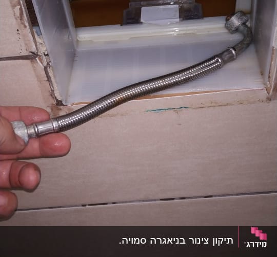 יד מחזיקה צינור גמיש ליד קיר פתוח